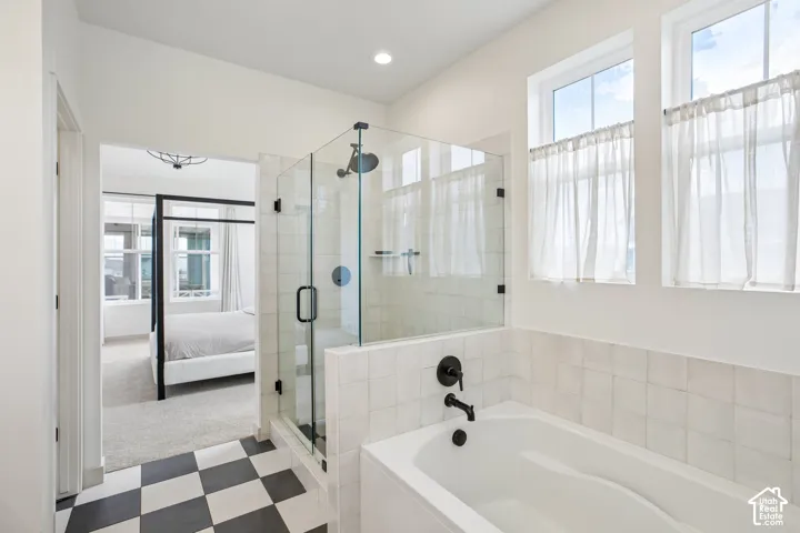Glass-enclosed shower with matte black fixtures, soaking tub with matte black fixtures, black and white checkered floor tiles, and upper windows