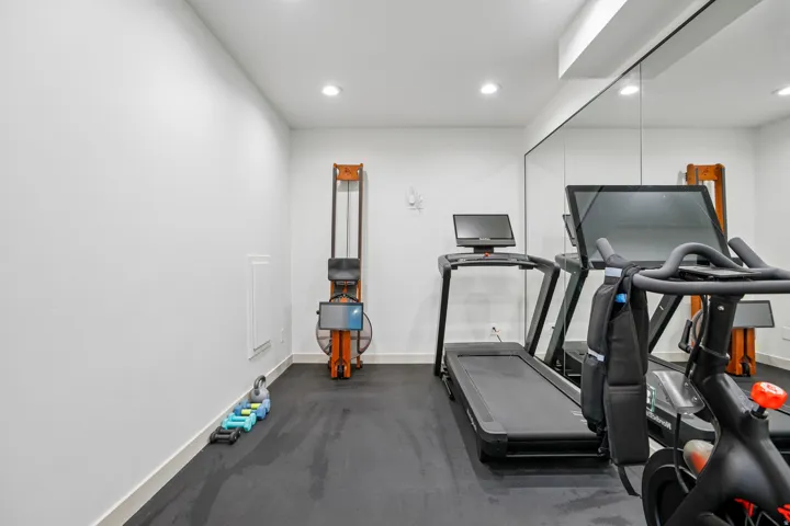 Dedicated exercise room featuring a mirrored wall, recessed lighting, and rubber flooring