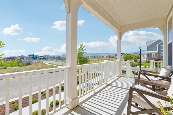 Covered front porch with white columns, balustrade, and a beadboard ceiling