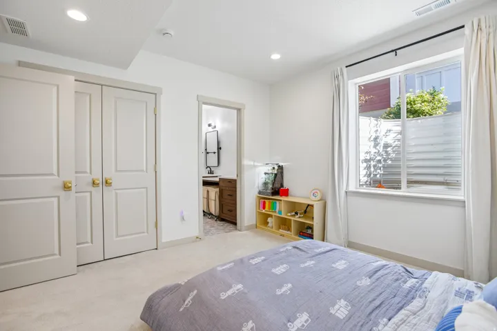 Recessed lighting, light-colored carpeting, and a window with white trim