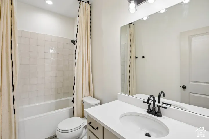 Bathroom featuring a single vanity with an integrated sink, matte black faucet, and a large mirror with overhead lighting