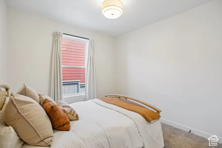 White walls, carpet flooring, window with vertical blinds, ceiling-mounted light fixture