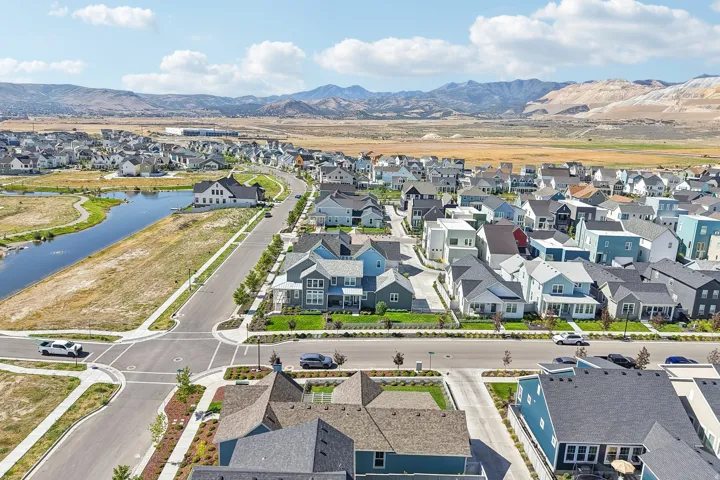 Aerial perspective showcasing a residential community with diverse home styles, a prominent waterway, and distant mountain scenery