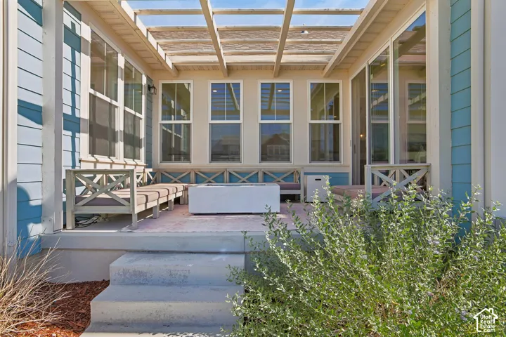 Covered patio with a slatted pergola, siding exterior, and multiple windows