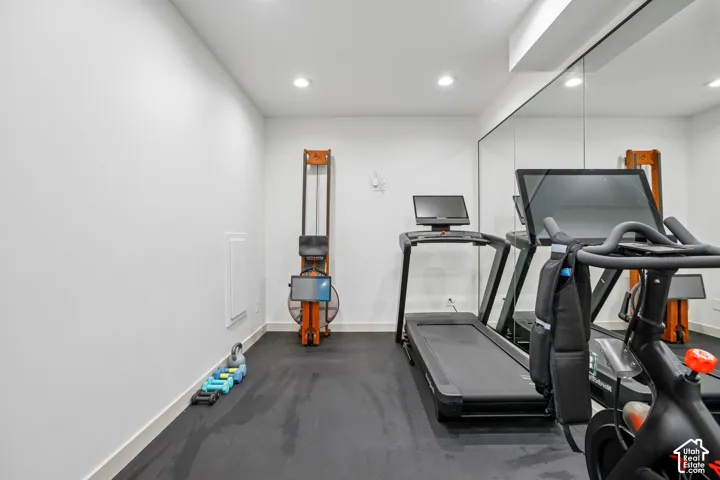 Dedicated exercise room featuring a mirrored wall, recessed lighting, and rubber flooring
