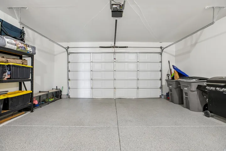Garage featuring an automatic overhead door, light gray epoxy flooring, and white walls