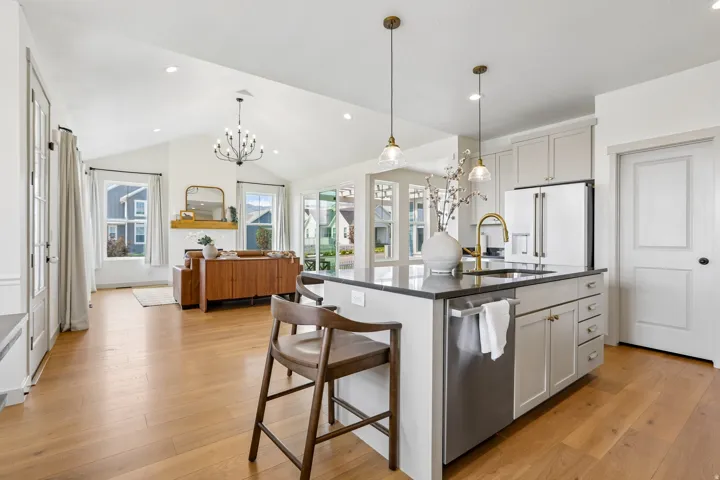 Open-concept living space featuring wood-finish flooring, vaulted ceilings, and recessed lighting