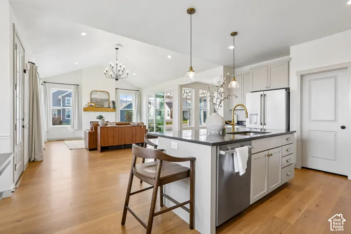 Open-concept living space featuring wood-finish flooring, vaulted ceilings, and recessed lighting