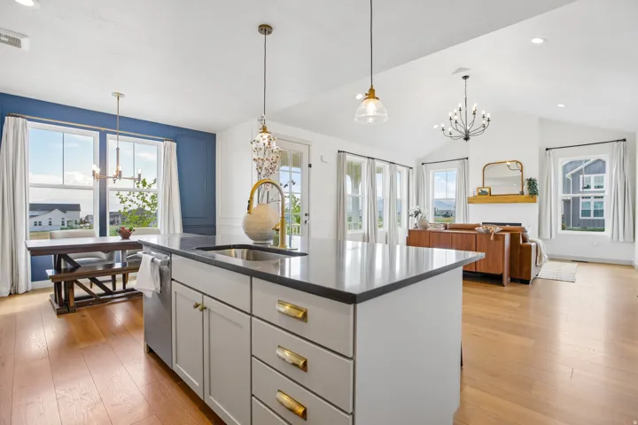 Modern kitchen island with integrated sink, wood-finish flooring, vaulted ceilings, and extensive window placements