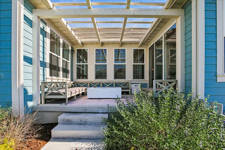 Expansive outdoor patio featuring a slatted pergola, concrete steps, and a built-in bench with decorative cross-bracing