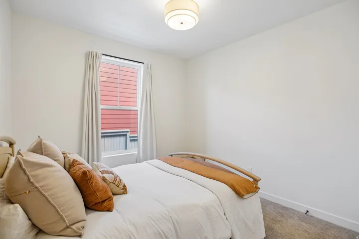 White walls, carpet flooring, window with vertical blinds, ceiling-mounted light fixture