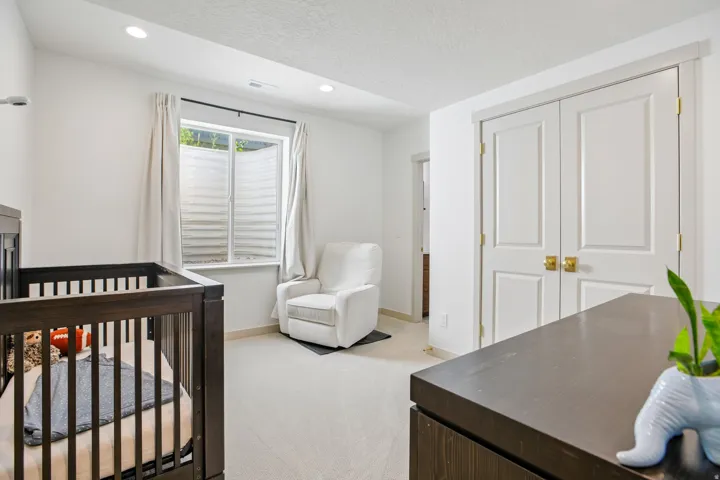 Recessed lighting, light-toned carpeting, window with privacy blinds, and white paneled double doors with brass-tone hardware