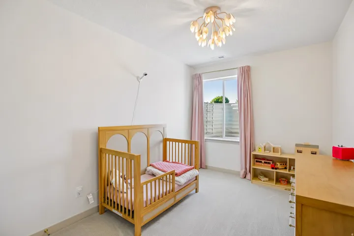White walls, light-colored carpeting, and a window with natural light