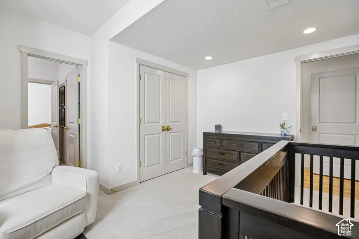 White walls with recessed lighting, light-toned carpet flooring, and white trim