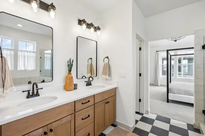 Double vanity with dual undermount sinks, quartz countertops, and wood-finish cabinetry