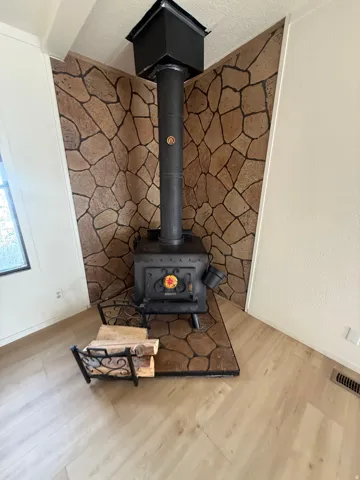 Wood-burning stove with a stone-clad wall and wood-finish flooring