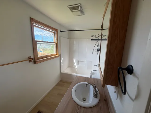 Bathroom with a wood-finish countertop, integrated sink, and an overhead mirrored medicine cabinet