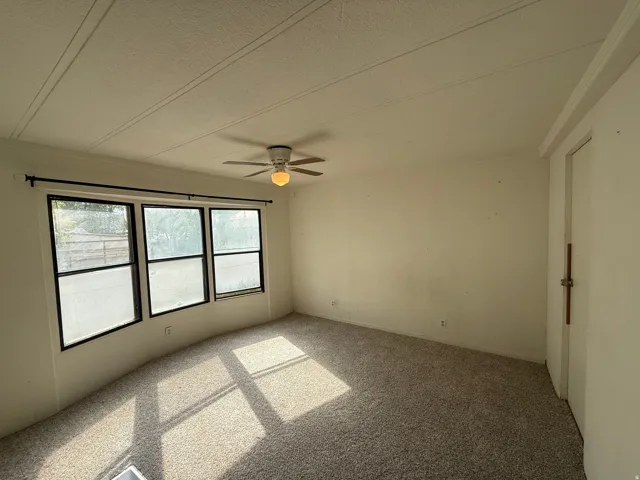 Wall-to-wall carpeting and a ceiling fan with integrated lighting