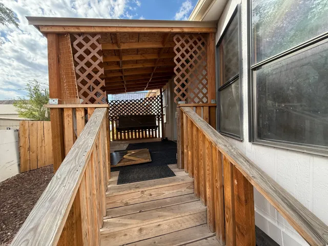 Covered porch with wood-finish lattice detailing, wood railing, and wood steps
