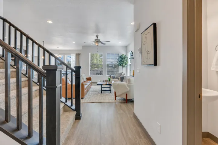 Wood-finish flooring throughout, carpeted staircase with dark wood newel posts and balusters, and recessed ceiling lighting