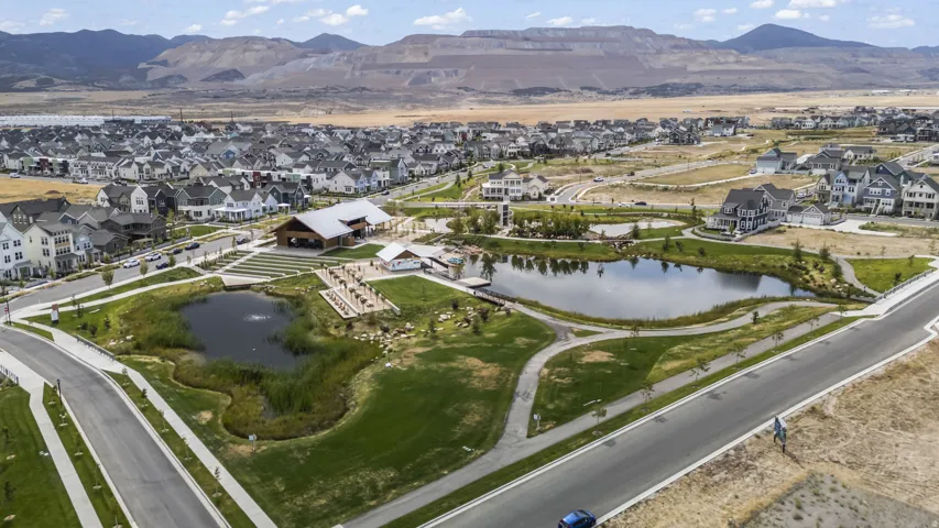 Community featuring two ponds, a central building with a covered patio, paved walking paths, and expansive green spaces