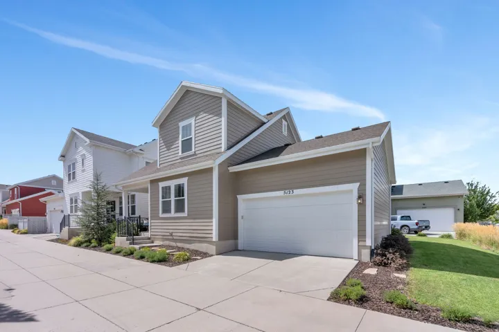 Contemporary two-story exterior with horizontal siding, an attached garage, paved driveway, and landscaping