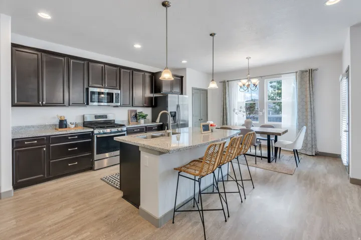 Kitchen featuring dark wood-finish cabinetry, stainless steel appliances, granite countertops, and wood-finish flooring