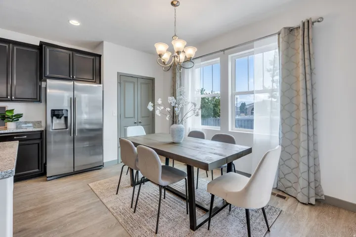 Stainless steel refrigerator, dark wood-finish cabinetry, light wood-finish flooring, recessed lighting, and a multi-pane window