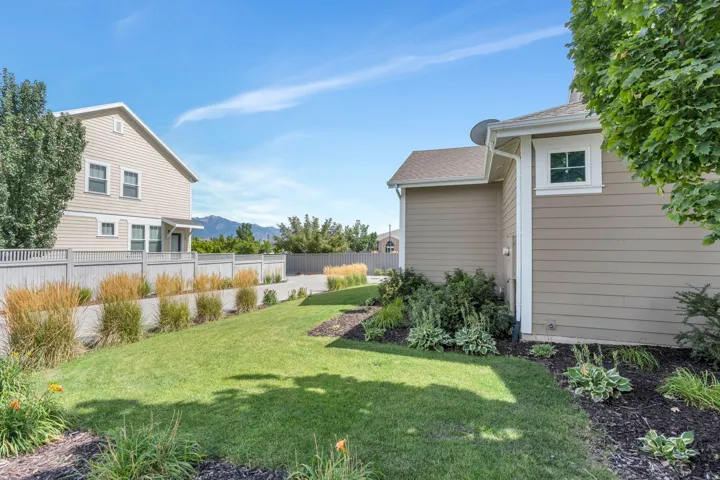 Manicured lawn with established landscaping, concrete pathway, and a privacy fence
