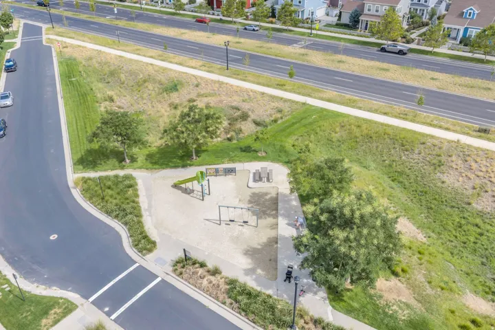 Outdoor play area with sand surface, swings, and a slide structure