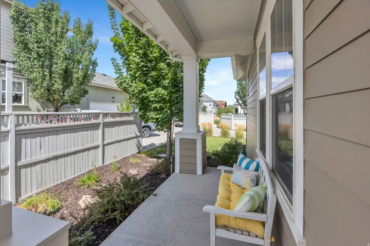 Covered concrete porch with white support columns, horizontal siding, and multiple windows