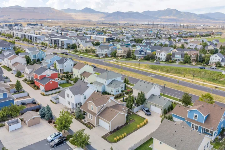 Aerial perspective showcasing a developed residential neighborhood with a variety of architectural styles, a paved street, and distant mountain backdrops