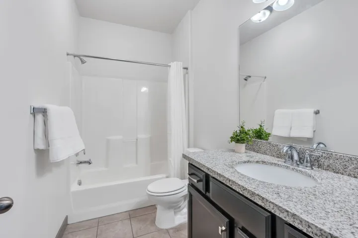 White tub and shower combination with a chrome shower head and faucet