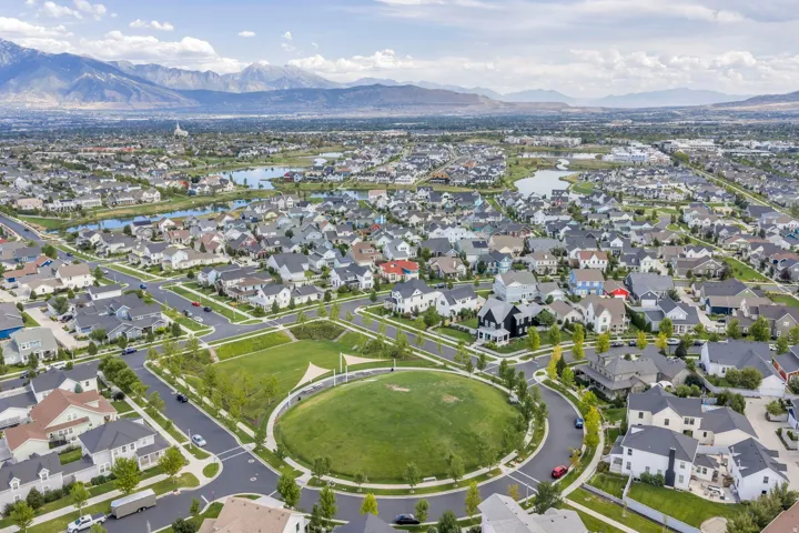 Expansive residential area featuring numerous detached homes, a central circular green space, and multiple neighborhood lakes