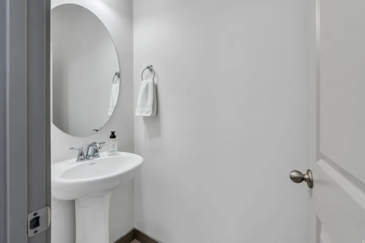 Pedestal sink with chrome faucet, oval mirror, and chrome towel ring