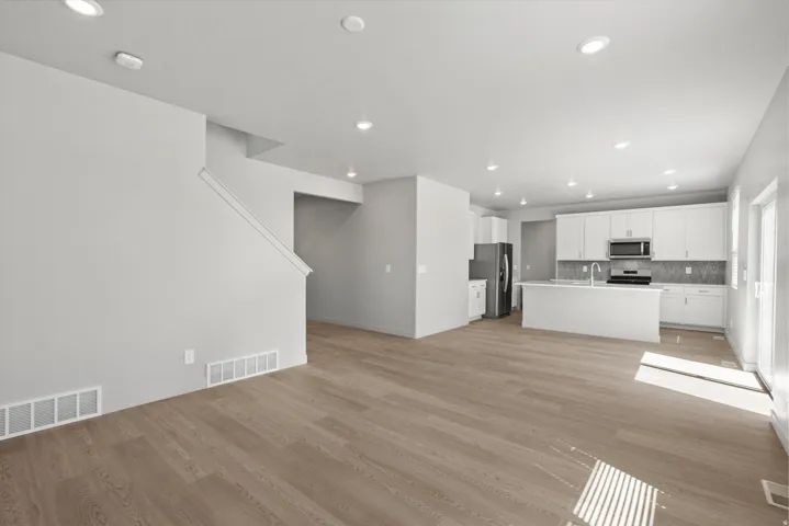 **Disclaimer** Interior package has upgrades not photographed.  Open-concept living space with wood-finish flooring, recessed lighting, and a modern kitchen