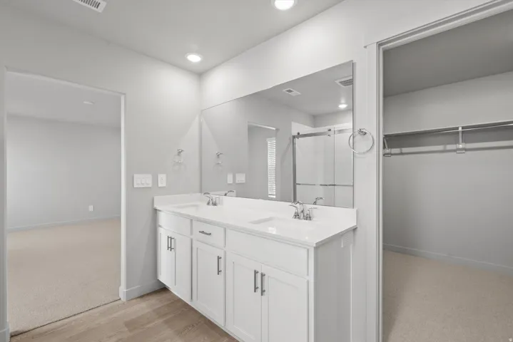 **Disclaimer** Interior package has upgrades not photographed.  Double vanity with white cabinetry and integrated sinks, a large mirror, and wood-finish flooring