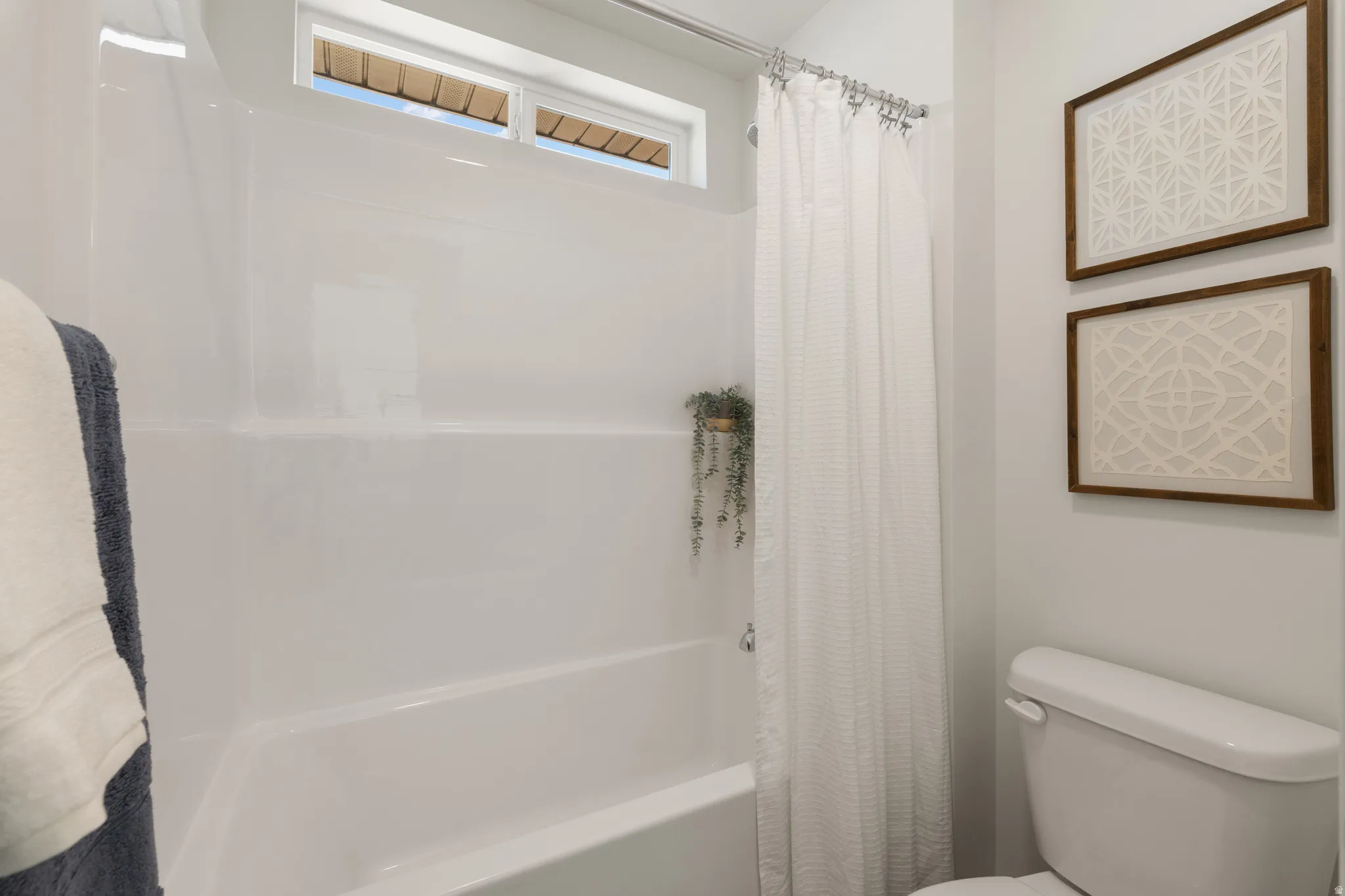 White tub and shower combination with an integrated shelf and frosted transom window