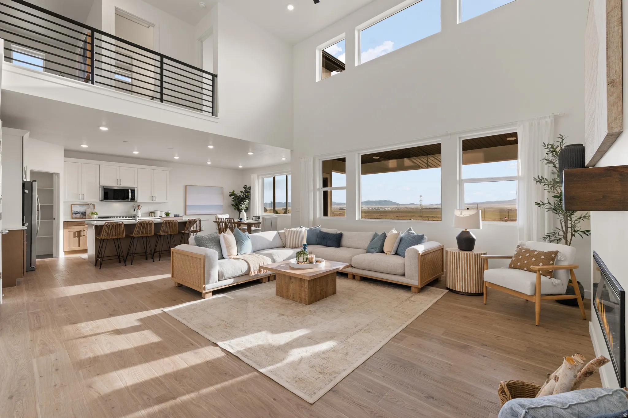Two-story living area with high ceilings, wood-finish flooring, and multiple windows