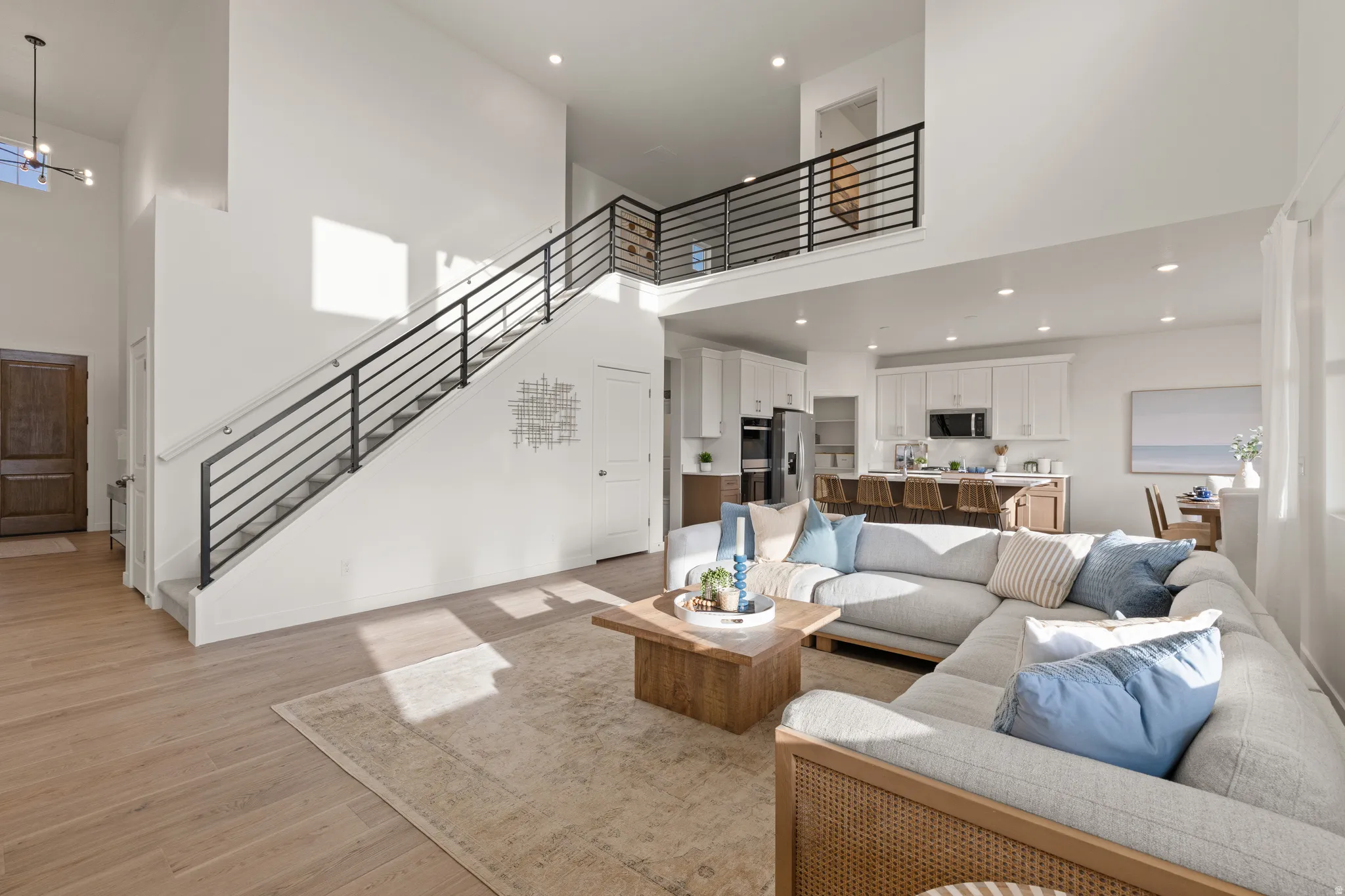 High ceilings with recessed lighting, wood-finish flooring, and a modern open-tread staircase with black metal railings