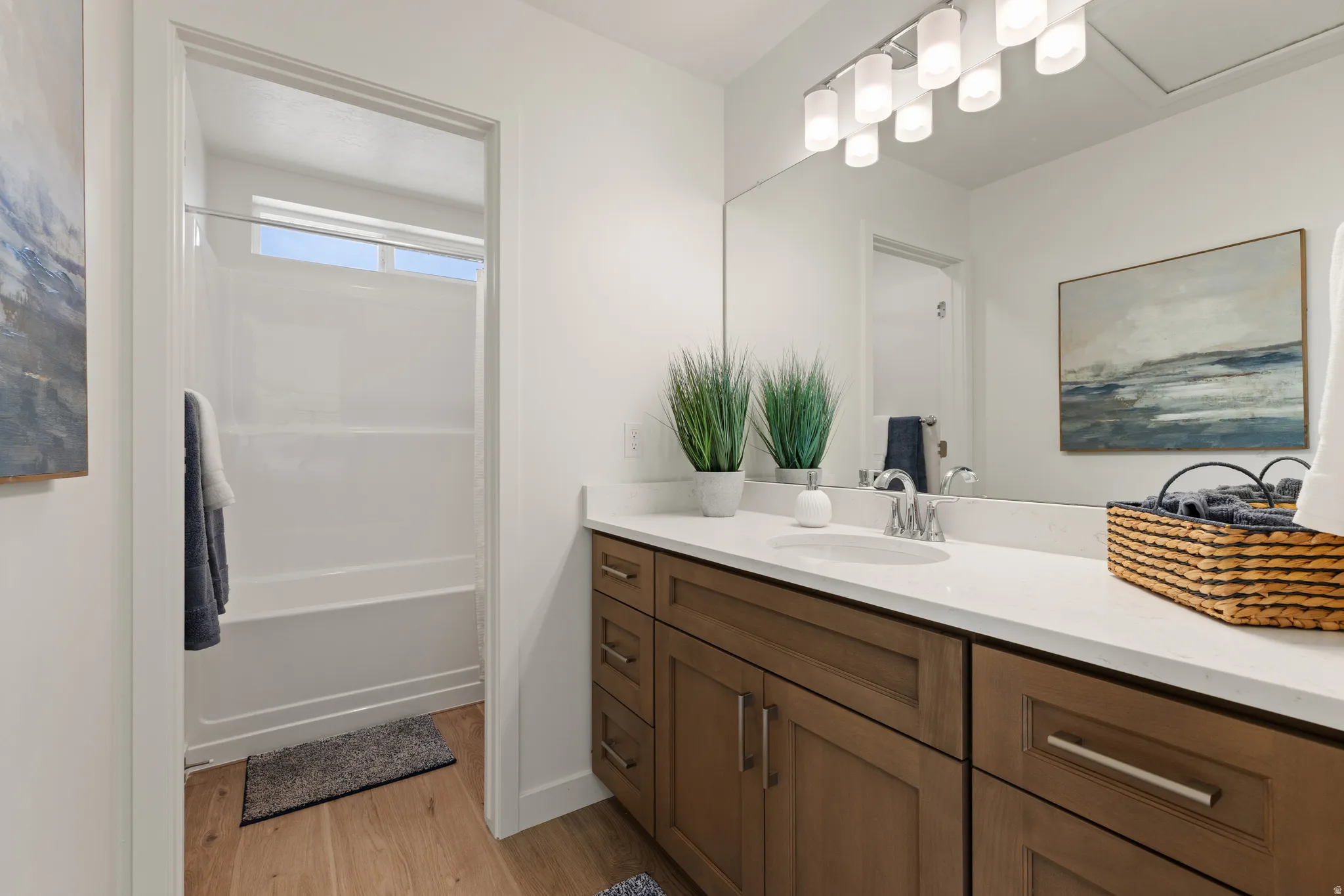 Spacious vanity with a light countertop, wood-finish cabinetry, and a full-width mirror
