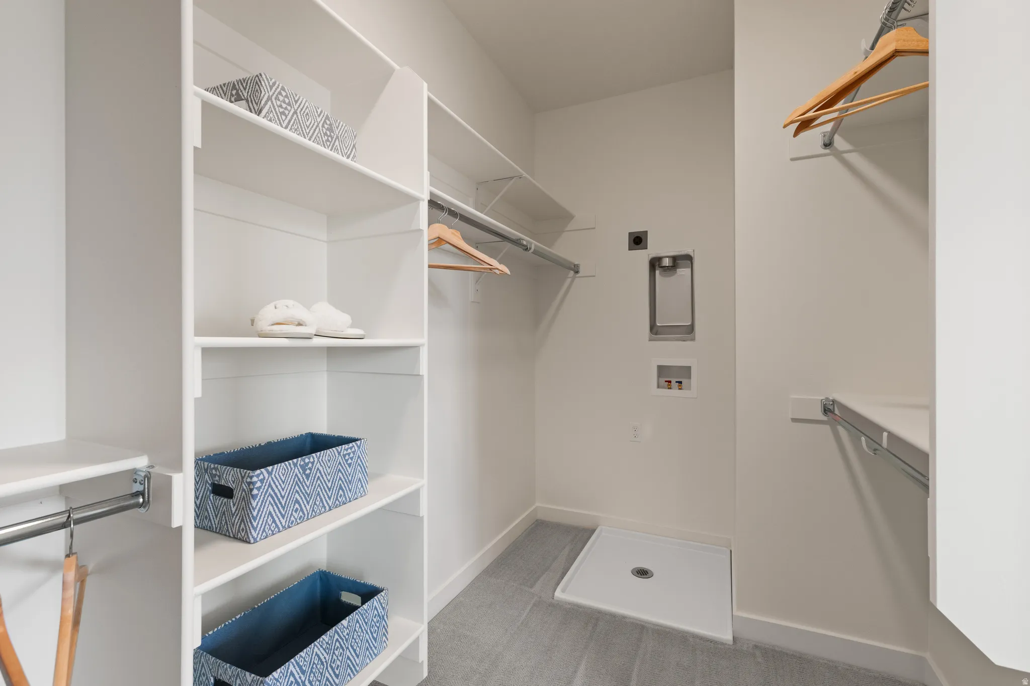 Integrated laundry area with utility hookups, built-in shelving, and hanging rods
