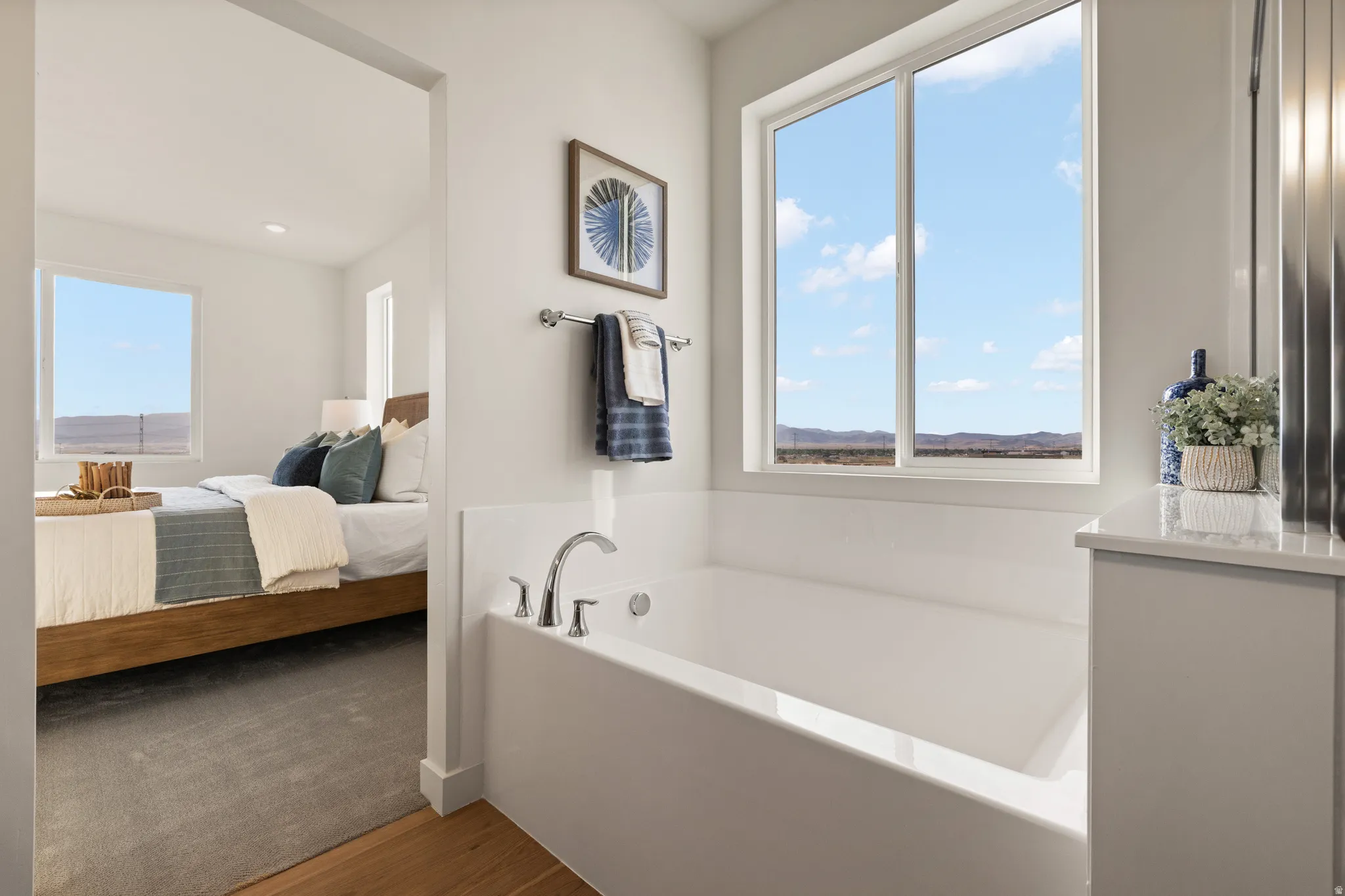 Built-in soaking tub with chrome fixtures, large window, and light-toned vanity with a solid surface countertop