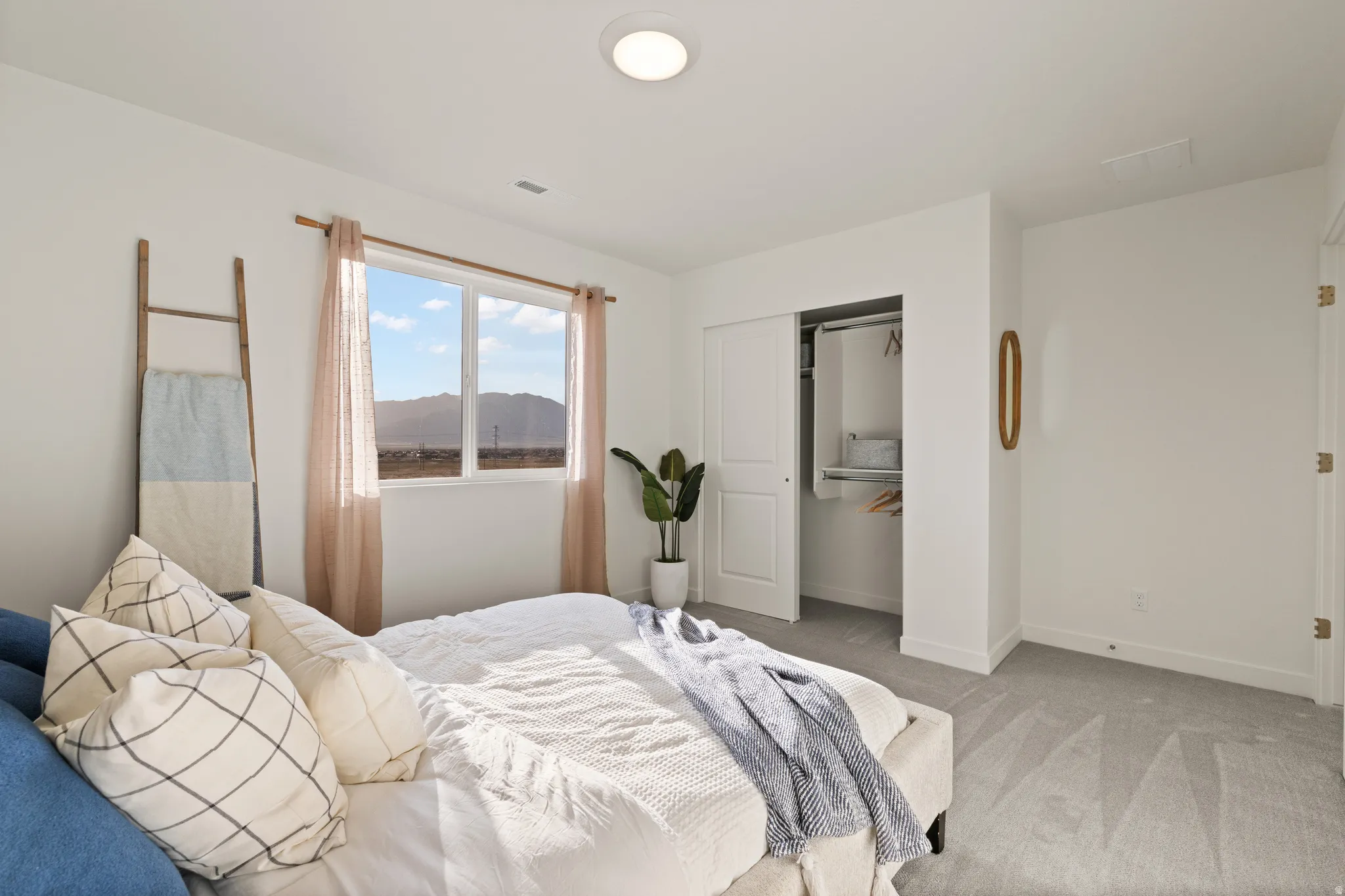 Recessed lighting, large window, mountain scenery, sliding closet doors, and light gray carpeting