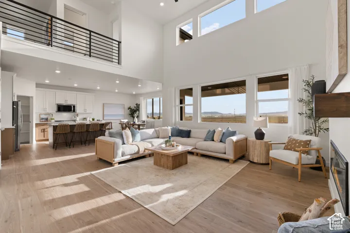 Two-story living area with high ceilings, wood-finish flooring, and multiple windows
