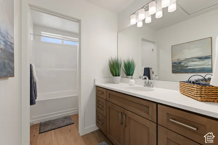 Spacious vanity with a light countertop, wood-finish cabinetry, and a full-width mirror