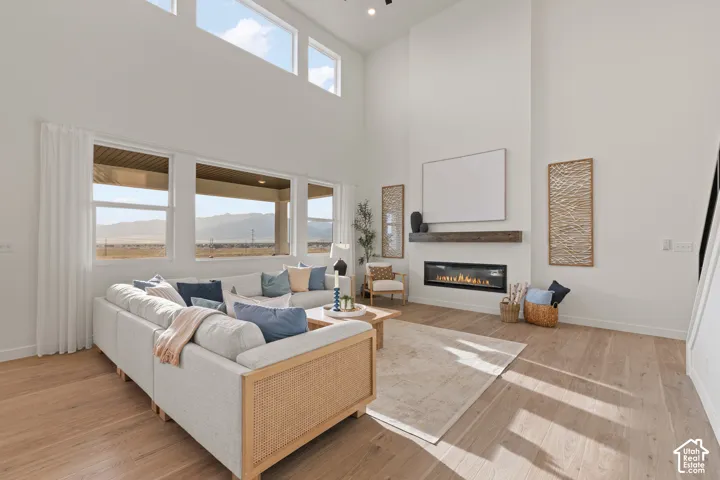 Vaulted ceilings, expansive windows, light wood-finish flooring, and a linear fireplace with a wood mantle