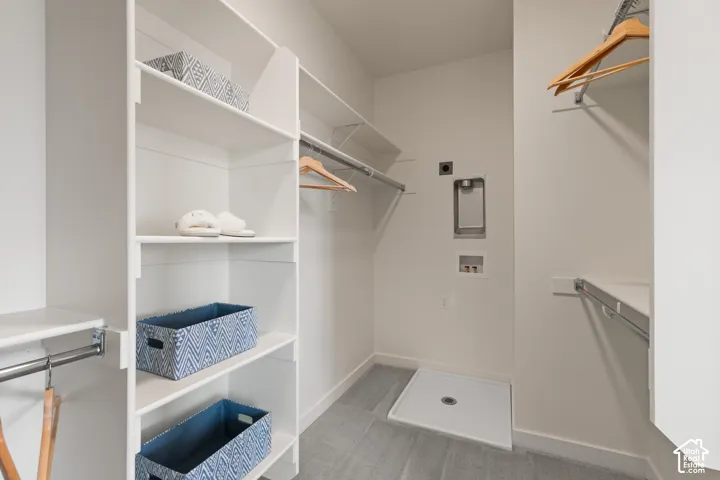 Integrated laundry area with utility hookups, built-in shelving, and hanging rods