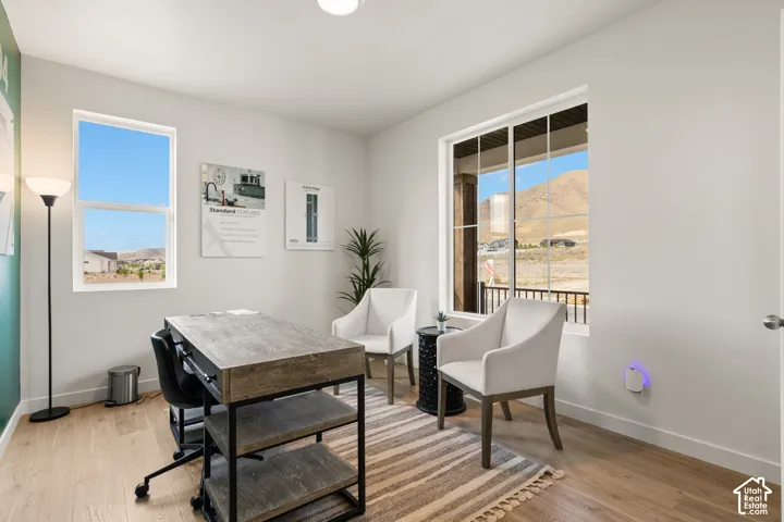 Light-filled interior space featuring large windows, wood-finish flooring, and white walls