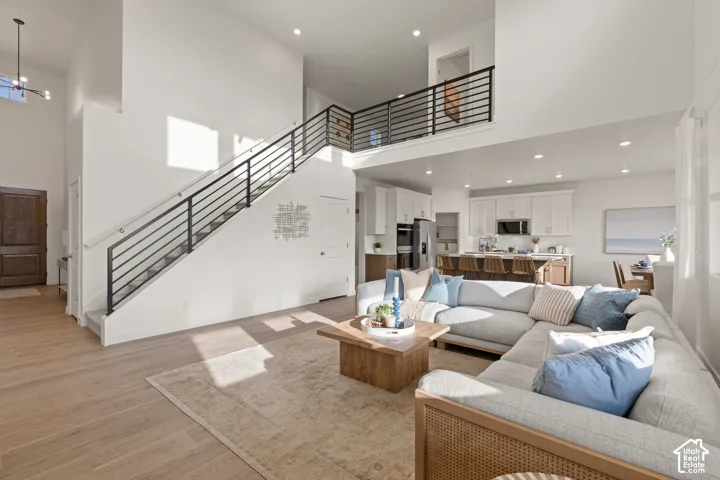 High ceilings with recessed lighting, wood-finish flooring, and a modern open-tread staircase with black metal railings